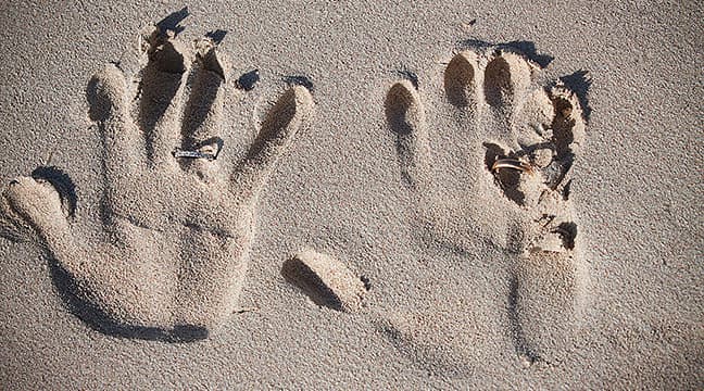 wedding rings with handprints in the sand